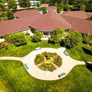 An aerial view of a building surrounded by lush greenery and a circular garden with benches.