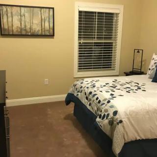 A neatly arranged bedroom with a bed, side table, lamp, and wall art.