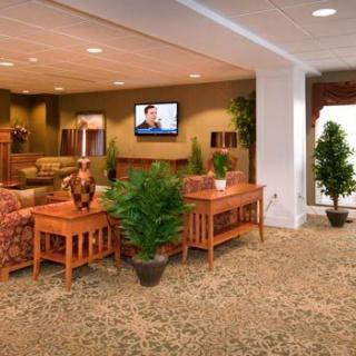 A cozy lobby area featuring comfortable seating, decorative plants, and a television mounted on the wall.