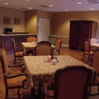 A cozy dining area with tables and chairs arranged neatly, featuring warm lighting and classic decor.