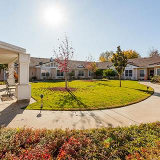 A scenic view of a courtyard with a well-maintained lawn and trees on a sunny day.