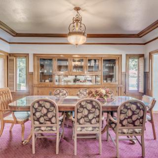 A classic dining room with a wooden table, floral upholstered chairs, and a chandelier.
