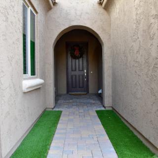 A welcoming entrance leading to a stylish front door, framed by an arch and lined with decorative grass.