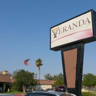 Veranda restaurant sign with building and parking lot in the background.