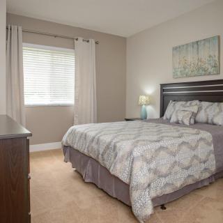 A cozy bedroom with a neatly made bed, soft lighting, and modern decor.