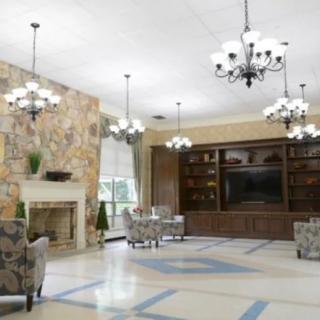 Spacious living area with chandeliers, a stone fireplace, and a built-in bookcase.