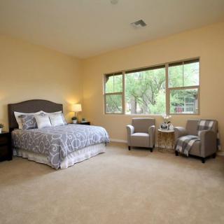 A spacious bedroom with a large bed, two chairs by the window, and soft lighting.