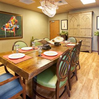 A cozy dining room with a wooden table set for a meal, featuring artwork and decorative elements.