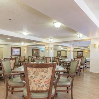 A spacious dining area with multiple tables and chairs, elegantly decorated with warm lighting.