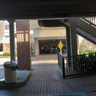 A view of a parking garage with a staircase and an outdoor area featuring a warning sign.