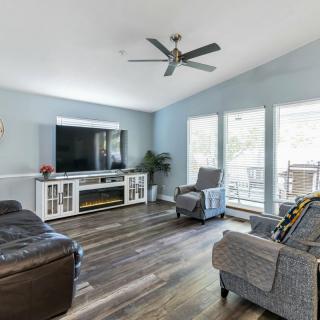 A modern living room with a large television, comfortable seating, and abundant natural light.