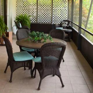 A cozy outdoor patio with a wicker table and chairs, surrounded by plants.