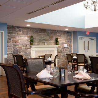 A modern dining room with elegant tables set and a stone accent wall.