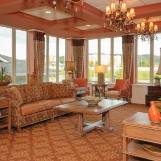 A cozy and stylish living room with large windows, elegant chandeliers, and comfortable furniture.