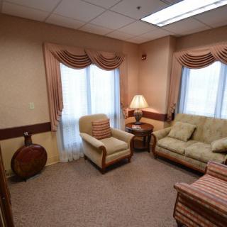 A cozy living room with a sofa, armchair, and decorative curtains.