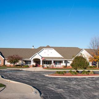 A suburban single-story residential building with neatly landscaped surroundings and a parking area.
