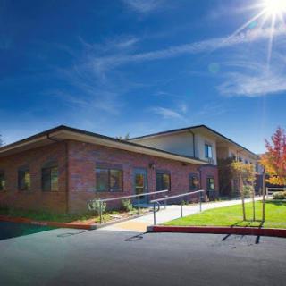 A modern brick building basking in sunlight, surrounded by green grass and a clear blue sky.