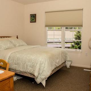 A cozy, well-lit bedroom with a bed, nightstand, and window featuring blinds.