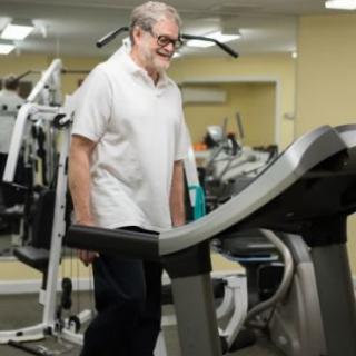 A senior man walking on a treadmill in the gym.