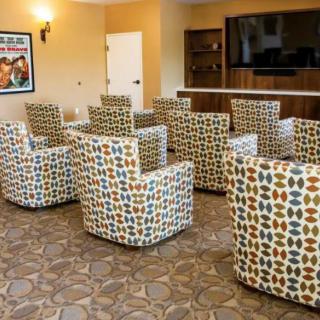 A cozy lounge area with patterned chairs arranged around a television, ideal for meetings or relaxation.
