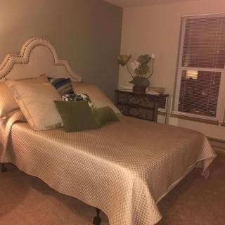 A cozy bedroom with a neatly made bed and warm lighting.