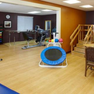 A rehabilitation room equipped with exercise machines, a trampoline, and stairs for physical therapy exercises.
