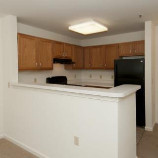 An apartment kitchen with wooden cabinets, black appliances, and a countertop.