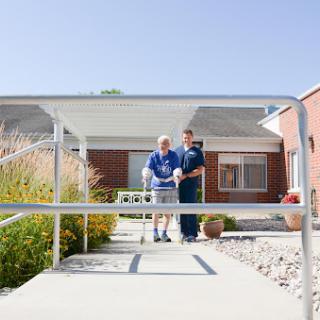 A caregiver assists a senior individual as they walk outside, showcasing the importance of support in rehabilitation.