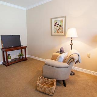 Cozy living room corner with a comfortable armchair, lamp, and television.