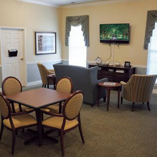 A cozy living room featuring a television, seating area, and a table with chairs.