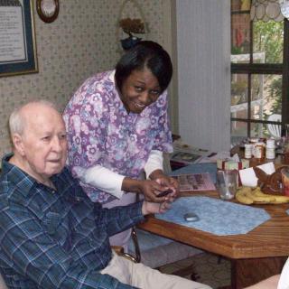 A caregiver assisting an elderly person in a home setting.