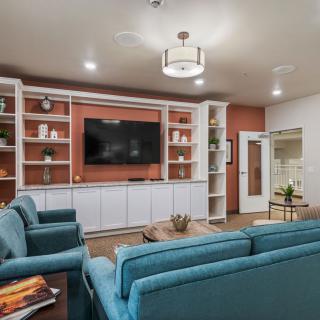 A modern living room with blue sofas, a large television, and built-in shelves.