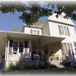A sunny day view of a residential house with a porch.