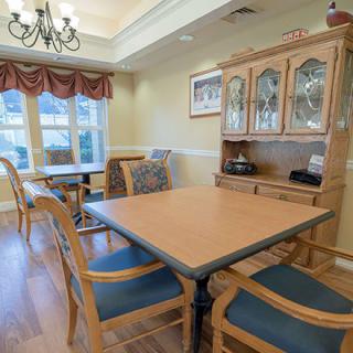 A cozy dining room featuring a wooden table with chairs, a cabinet, and large windows allowing natural light.