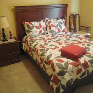 A cozy bedroom with a floral-patterned bedspread, pillows, and neatly folded linens on the bed.