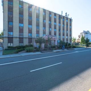 A multi-story building viewed from across a city street under bright sunlight.