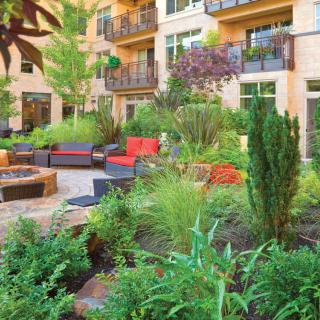 A lush garden courtyard with modern outdoor seating in an apartment complex.