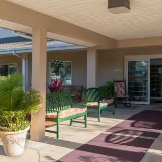 A welcoming porch area with benches and potted plants.