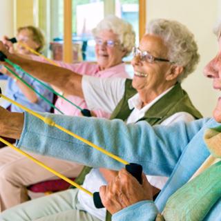 A group of elderly women participating in a fitness class using resistance bands.