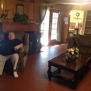 A person sitting on a couch in a cozy living room with wooden walls and furniture.
