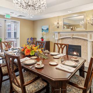 An elegantly decorated dining room featuring a set table, chandelier, and fireplace.