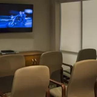 An office waiting room with chairs and a television displaying a scene.
