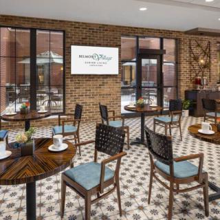 A cozy cafe interior with wooden tables and chairs, against a brick wall backdrop.