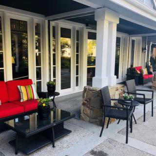 A cozy outdoor patio with red-cushioned furniture and tables set for relaxation.