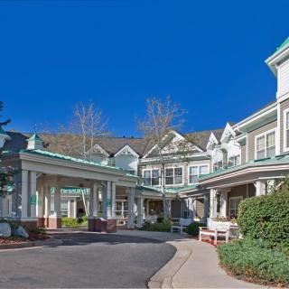A large residential building with a covered entrance and landscaped surroundings on a clear day.