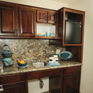 A kitchen with wooden cabinets, a granite countertop, and various appliances.