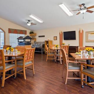 A cozy dining area with wooden tables and chairs, featuring warm lighting and decor.