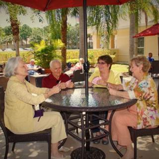 A group of elderly women enjoying a card game together on a sunny patio.