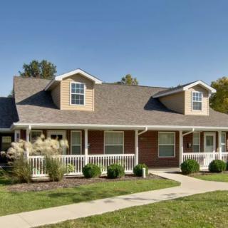A charming suburban house with a front porch and well-maintained lawn.