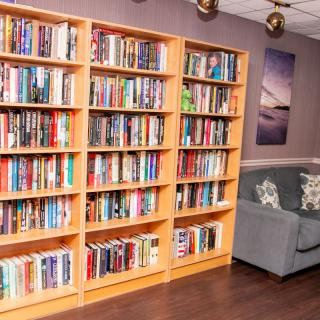 A cozy reading corner with a large bookshelf filled with various books and a comfortable sofa.